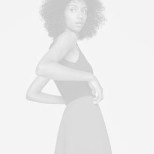 Modelo en blanco y negro con vestido elegante y cabello rizado, mirando hacia la cámara.