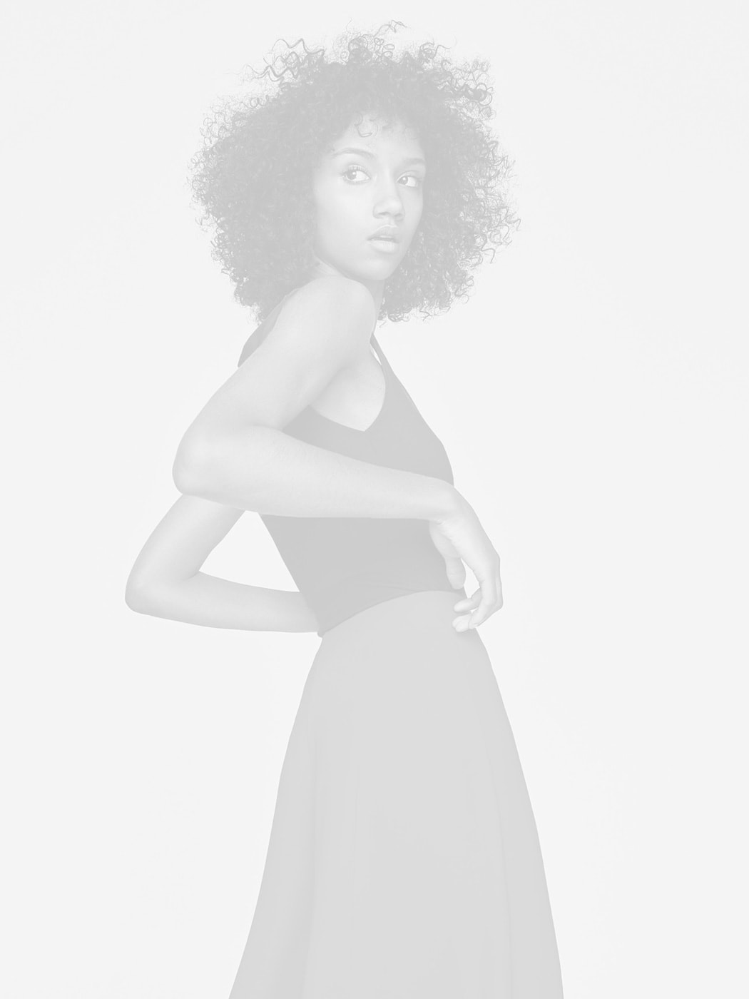 Modelo en blanco y negro con vestido elegante y cabello rizado, mirando hacia la cámara.